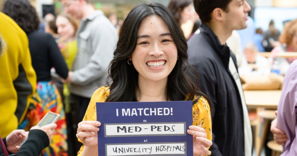female student smiling with a paper that reads "I matched in med-peds at University Hospitals"