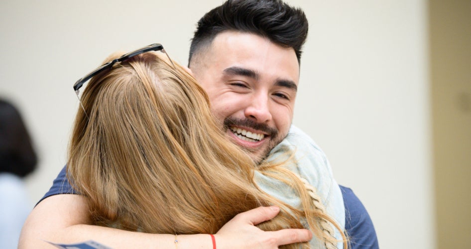 male student hugging someone at match day
