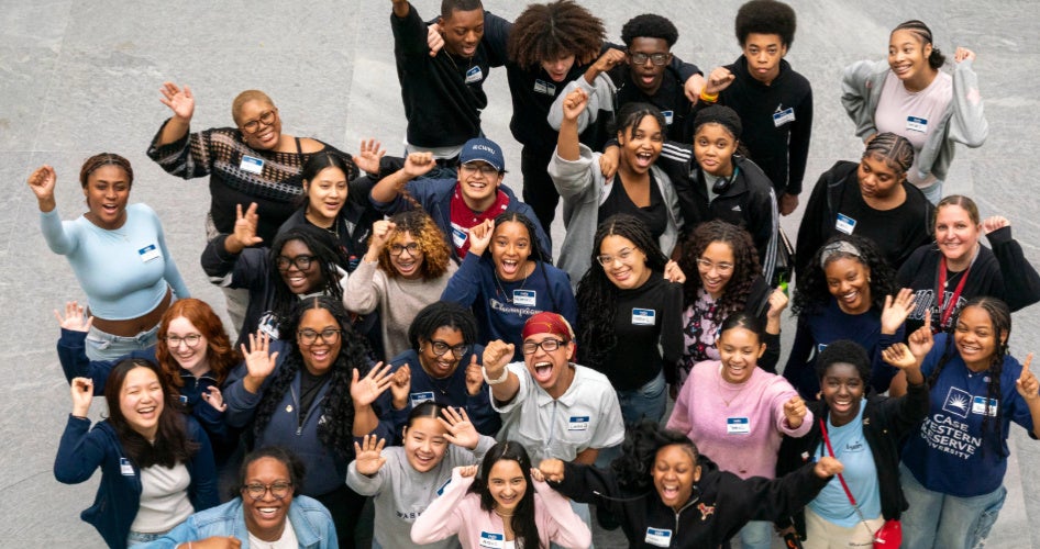 A large group of people stands in a group smiling up at a camera.