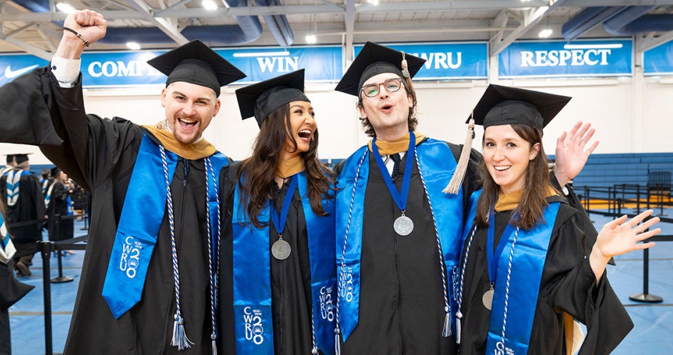Four master’s-level graduates pose together for a celebratory photo before their ceremony