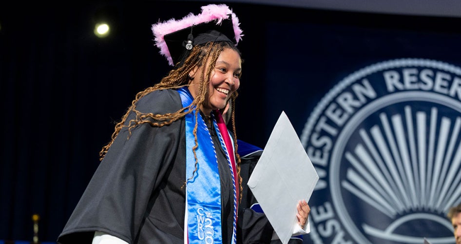 Photo of a smiling as she walks across the stage with her diploma