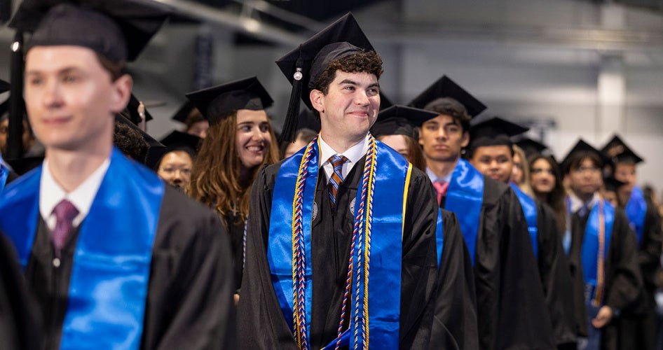 Photo of CWRU undergraduates at commencement as they stand with the focus on one smiling student