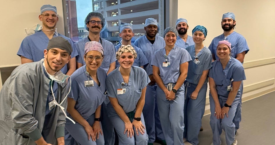Dental students in blue scrubs pose in a group.