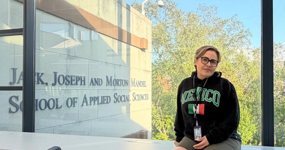 Edith Cabrera in front of a window with the Mandel sign behind it.