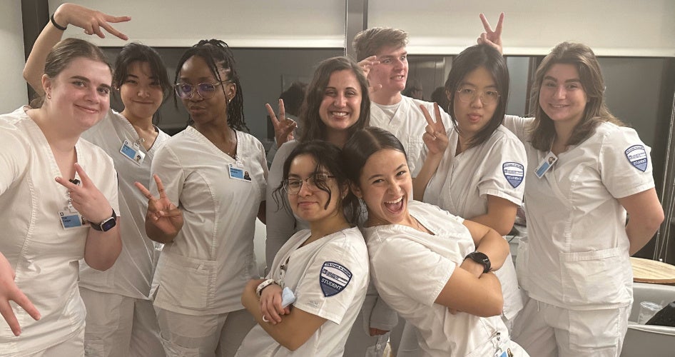 A group of nurses poses in white scrubs.