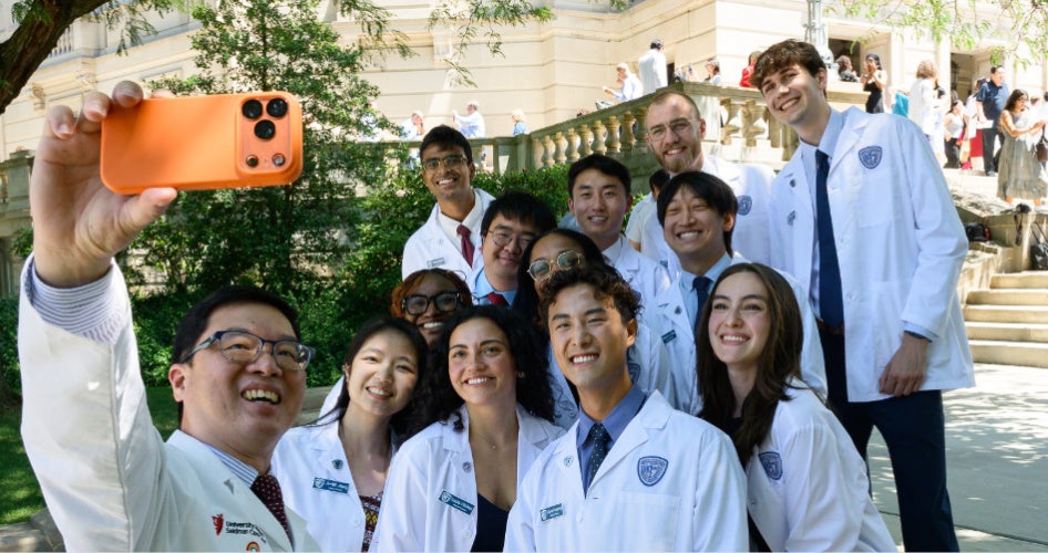 students posing for a selfie in their white coats