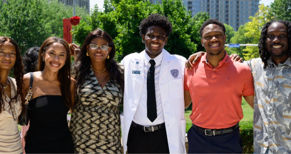 a new student in their white coat posing with family and friends
