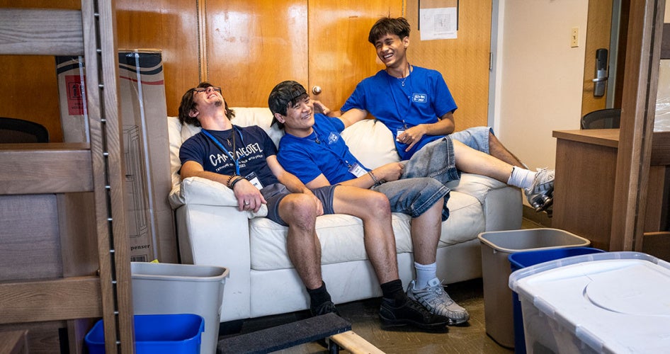 CWRU orientation leaders take a break during move-in by relaxing on a couch they just moved into a room