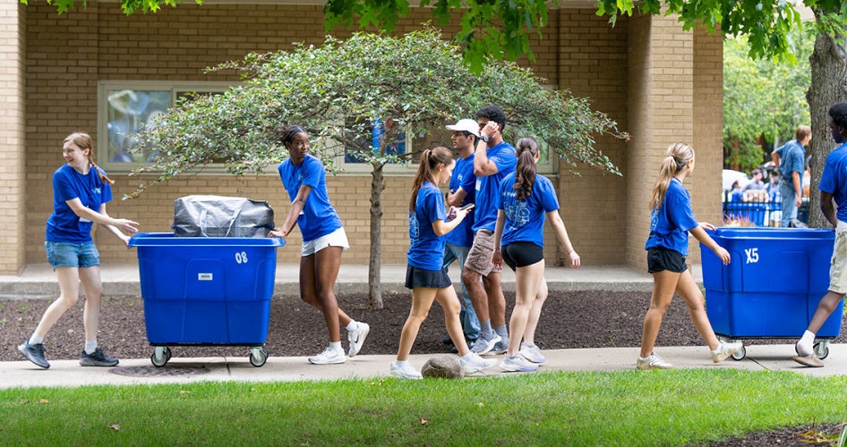 Orientation leaders move past one another with carts during move-in