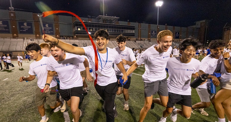 A group of new CWRU students run energetically on the football field during the tradition event