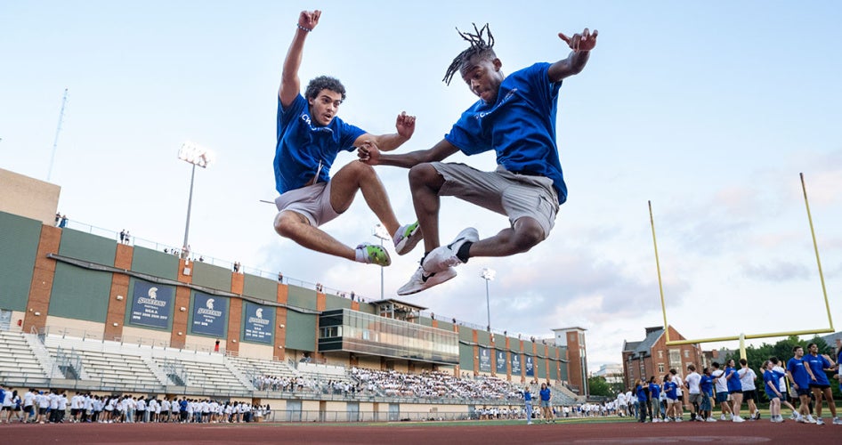 Two orientation leaders leap into the air to click their heels