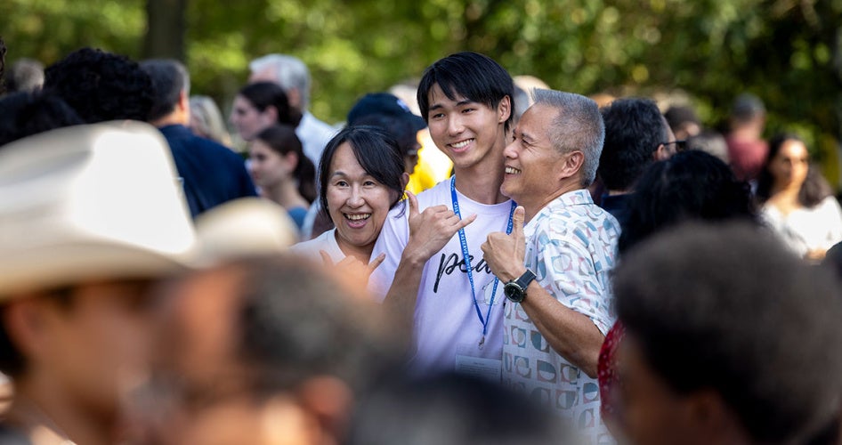 Parents hug their son as with a crowd of blurred people around them