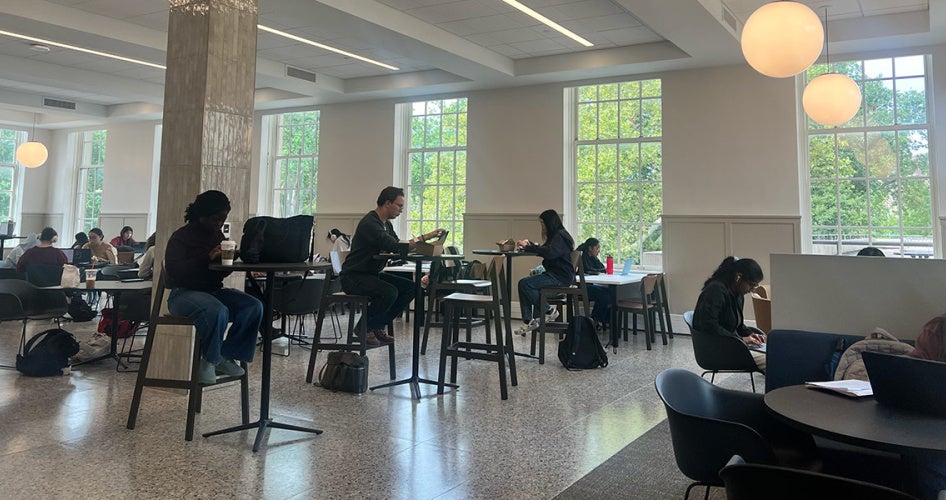 Students and employees sit at tables in the renovated Tomlinson Hall space