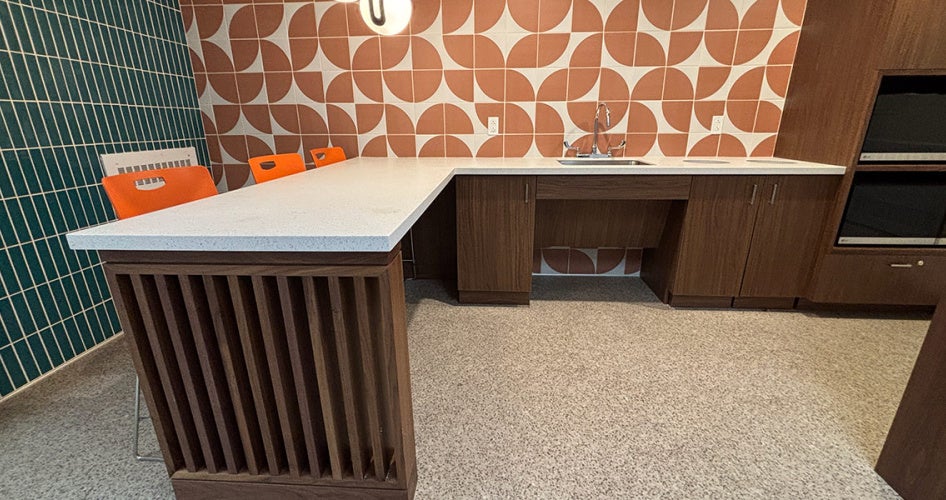 Photo of an L-shaped counter space in Sherman House's kitchen area with orange and teal tile backsplashes