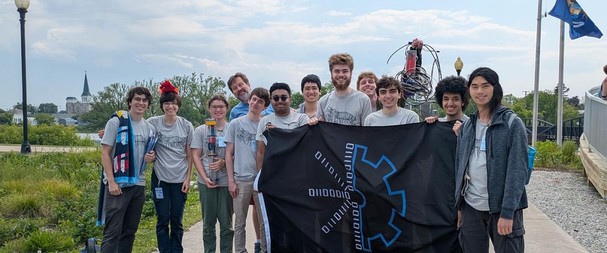 CWRUbotix team posing for a photo while holding their flag