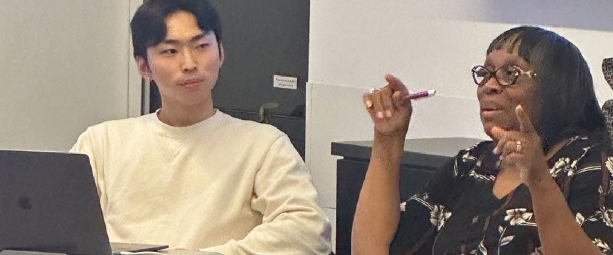 One student looks on as another talks to the class