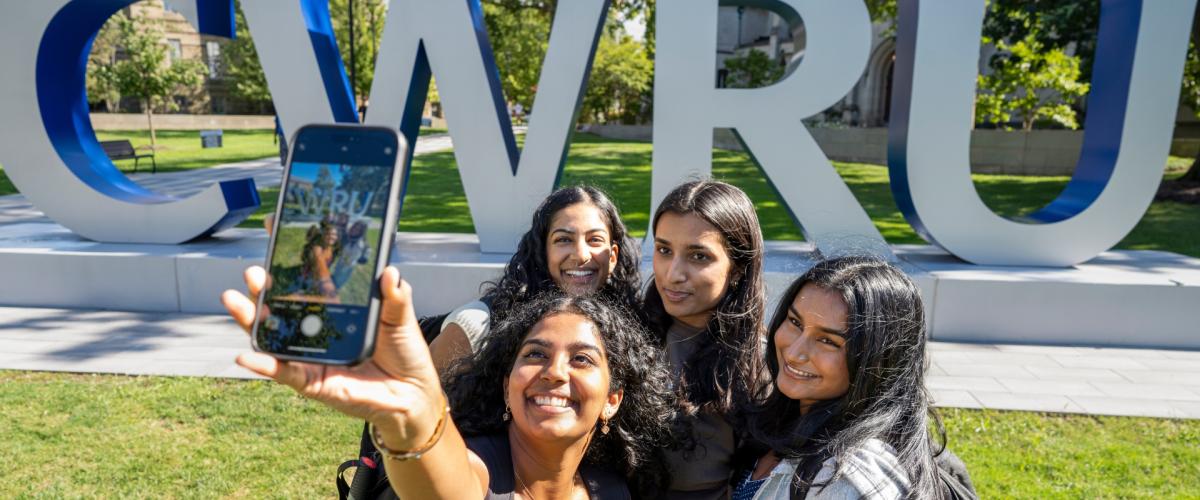 A group of students take a selfie near the big CWRU letters on the first day of classes.