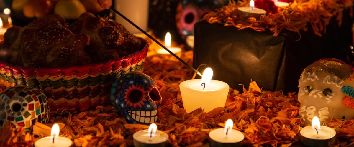 A person lights a candle sitting on an ofrenda for Dia de los Muertos (or Day of the Dead). 