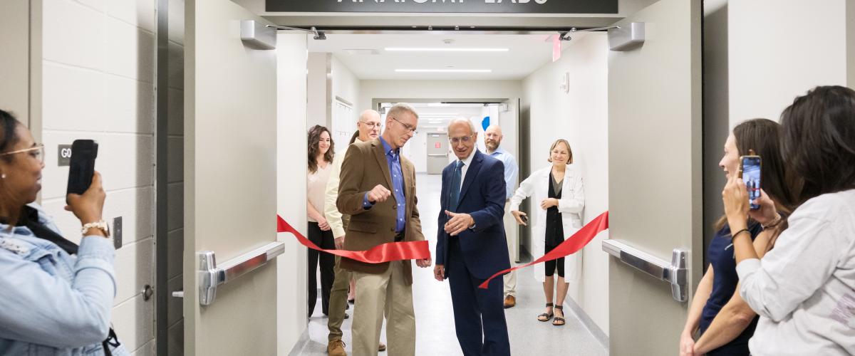 Stan Gerson and Darin Croft cutting a red ribbon at the doors of the new anatomy lab