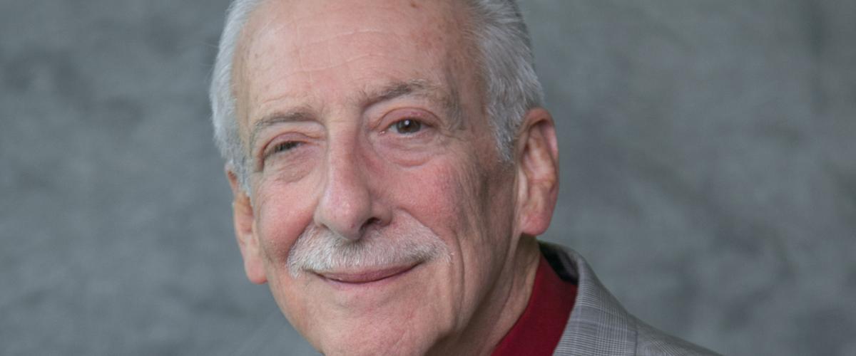Man wearing grey jacket with a orange tie and maroon shirt