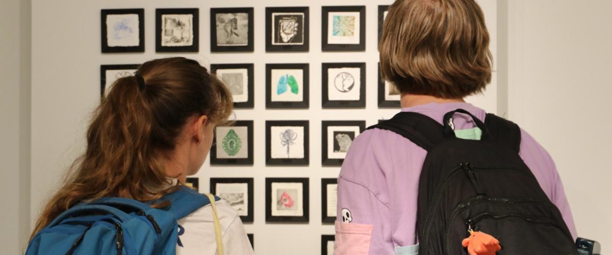 Back view of students looking at a display at Sears think[box]'s Open Print Exchange exhibit. 