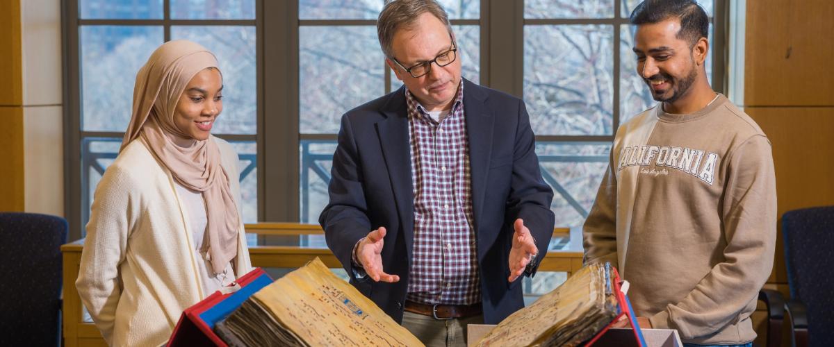 William "Bill" Claspy showcases vintage book with two members of the CWRU community. 