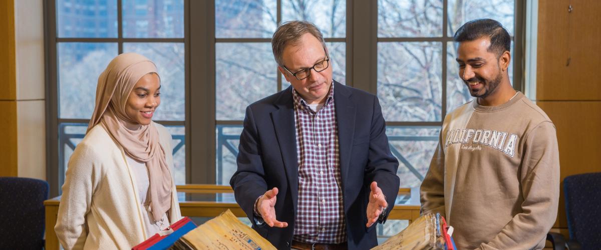 William "Bill" Claspy showcases vintage book with two members of the CWRU community. 