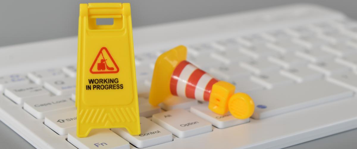 Mini "Work in progress" and construction signs on computer keyboard.
