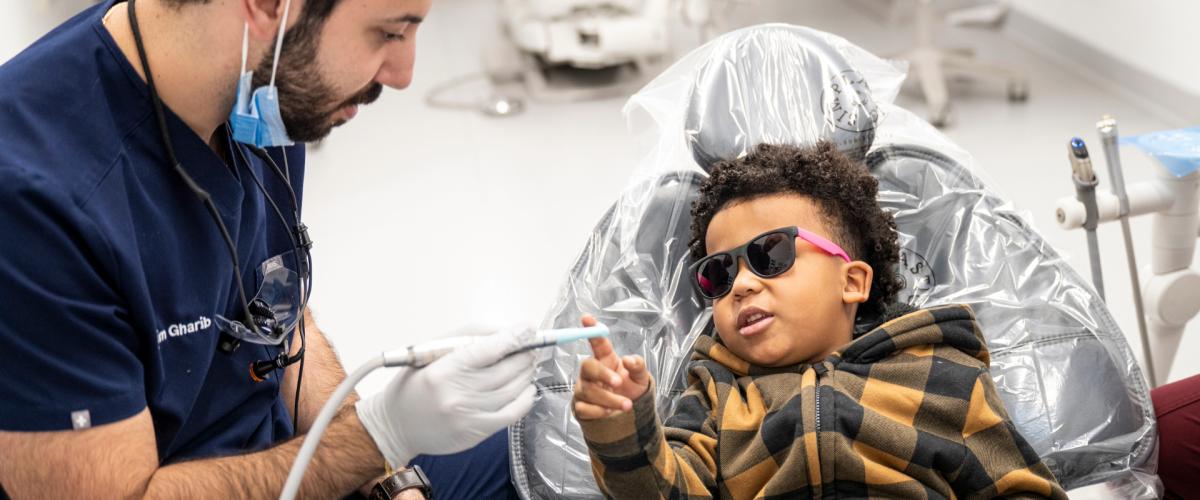 CWRU School of Dental Medicine student Karim Gharib shows dental tools to a child in the dental chair.