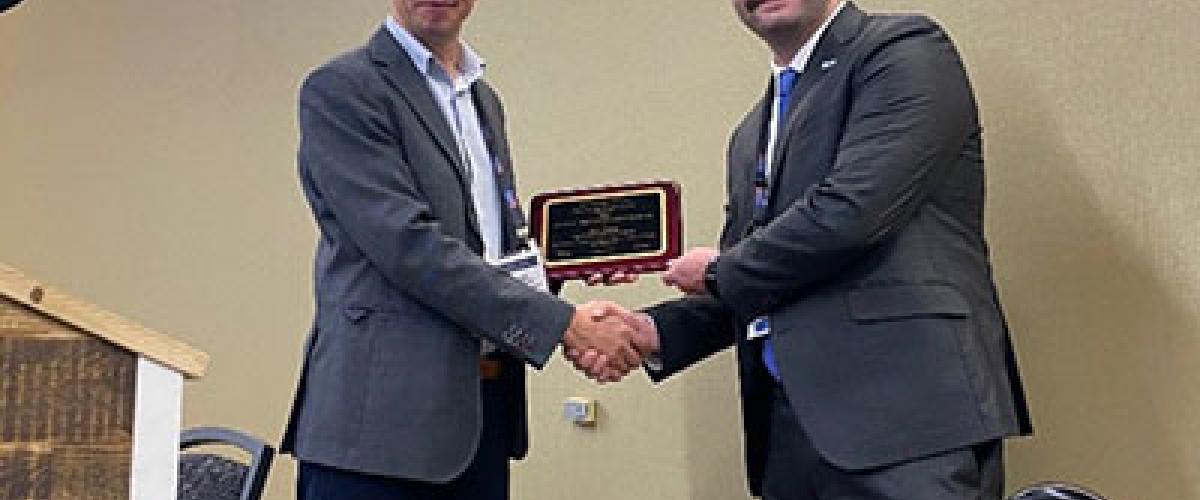 Photo of two men shaking hands as one accepts an award