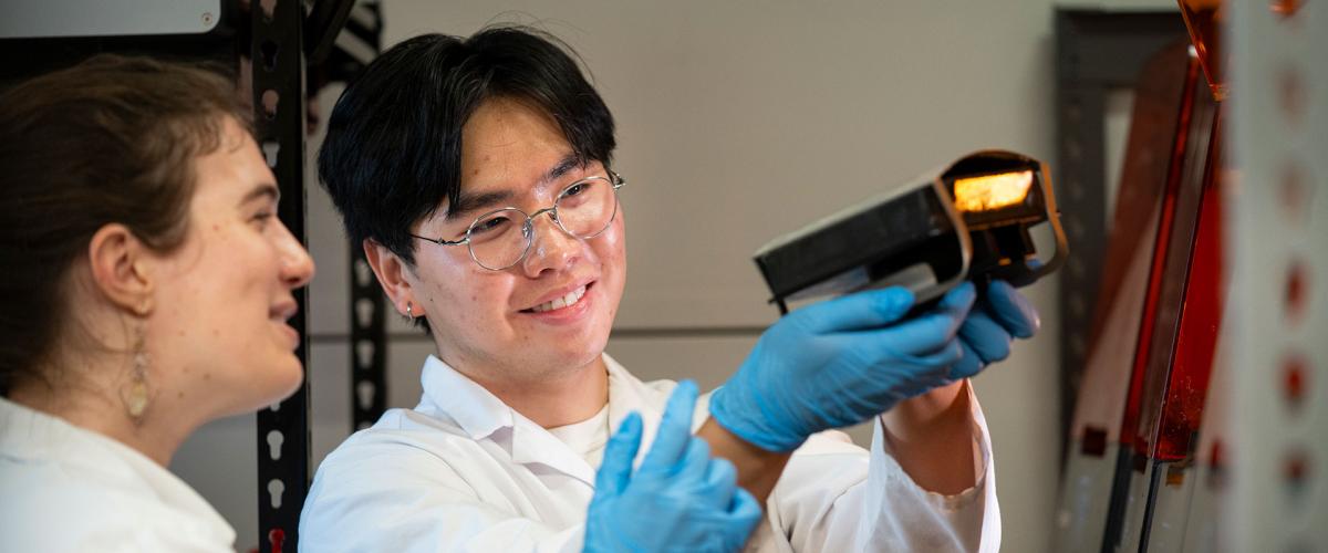 Photo of two CLEANR employees looking at a 3D printer part