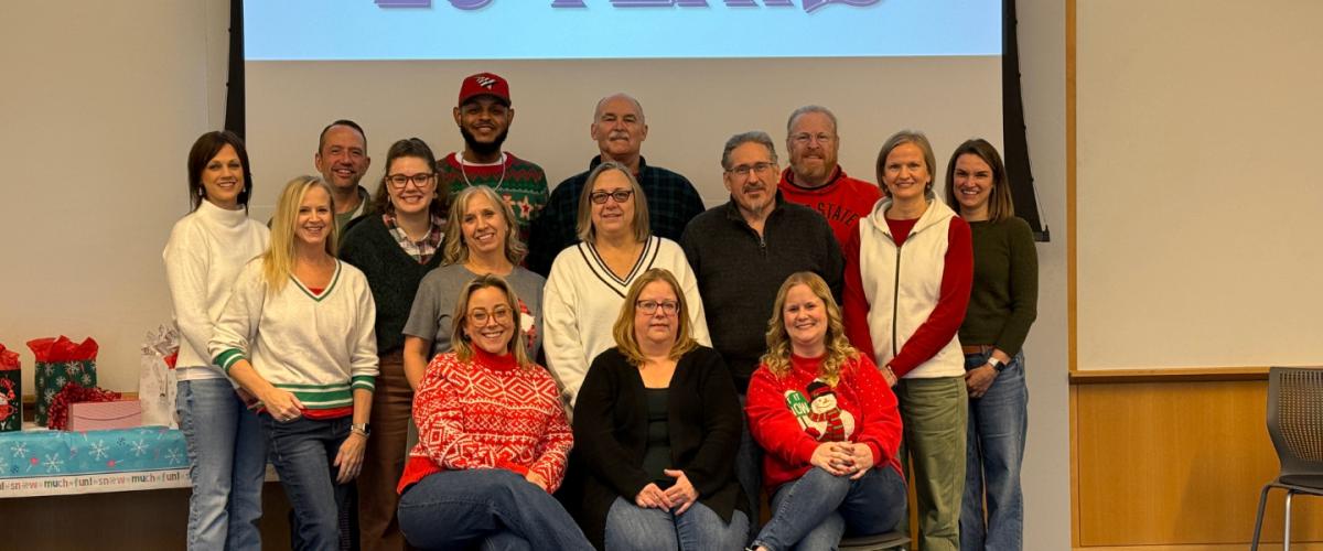 Staff members from the Center for Evidence Based Practices standing under a screen that says "CEBP 25 Years"