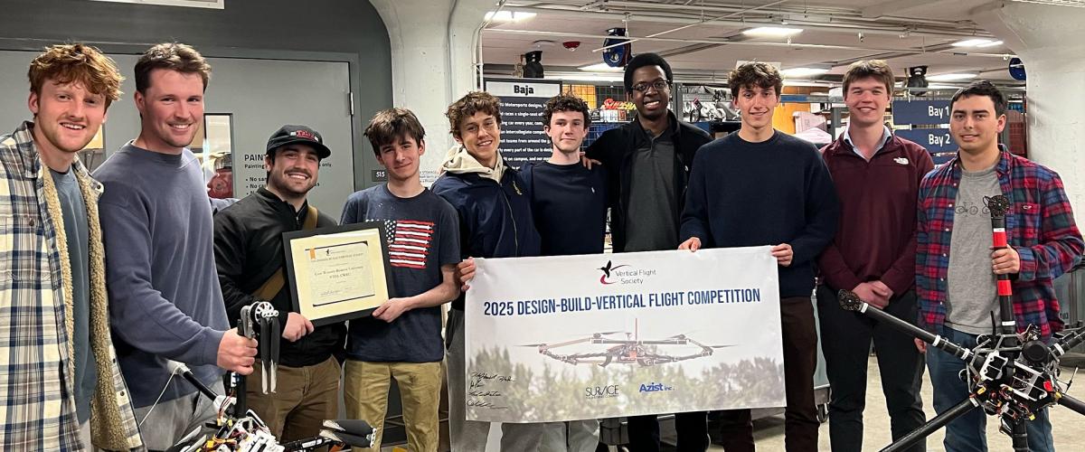 Members of VTOL gather for a photo with their team banner