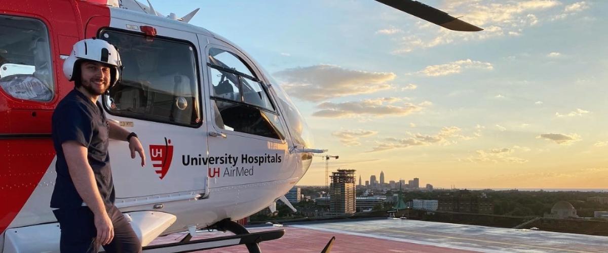 CRNA student Robert Sharkey stands in front of a medical helicopter on a rooftop.
