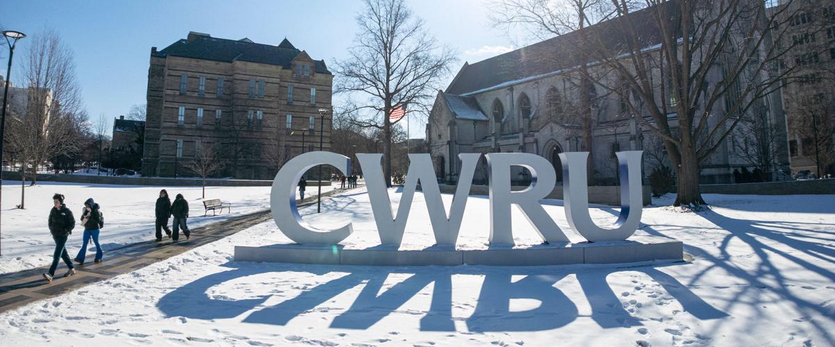 Photo of the CWRU letters on a snowy day with Adelbert Hall and Amasa Stone Chapel behind them