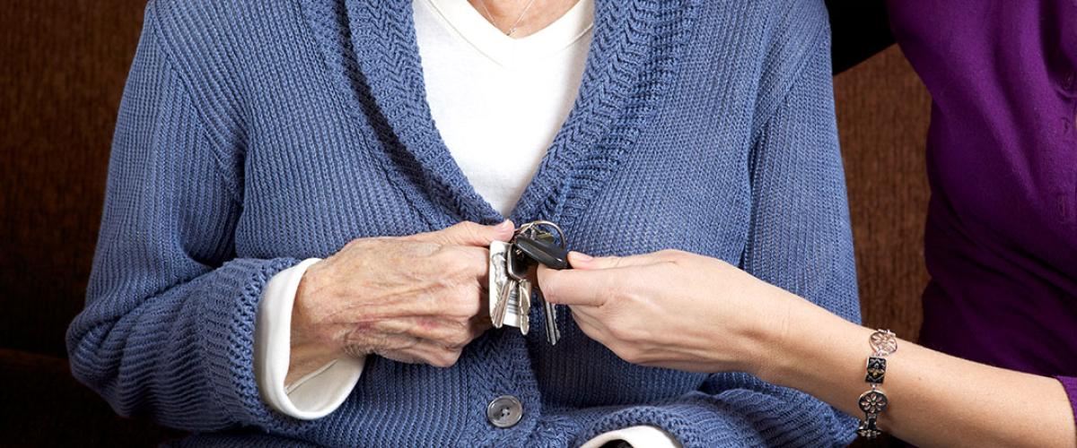 Photo of an elderly woman handing car keys to another person