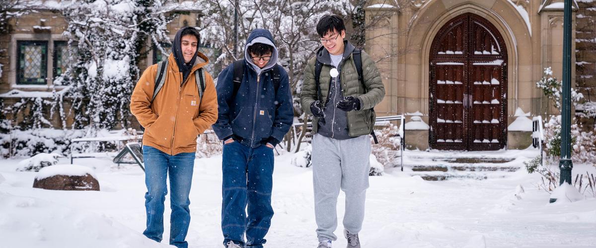 Photo of three students walking across Mather Quad on a snowy day