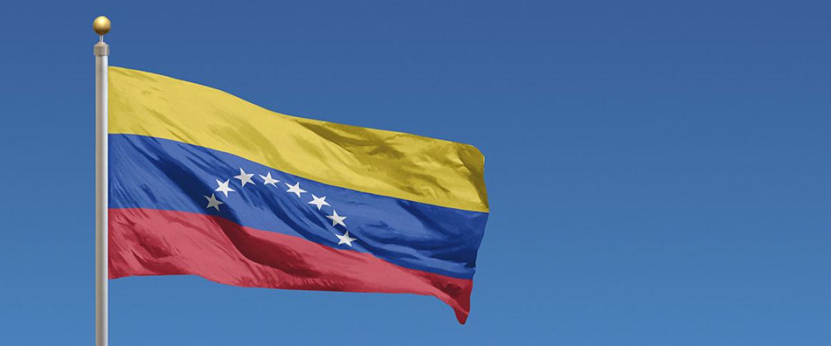 Photo of the Venezuelan flag flying against a blue sky
