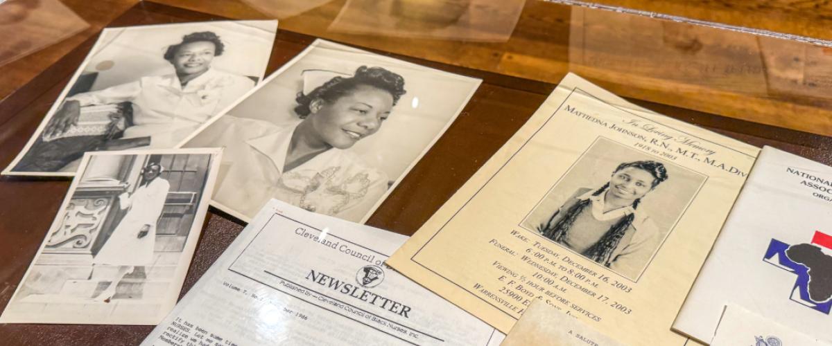 A selection of papers feature photos of Black nurses are spread out in a display case.