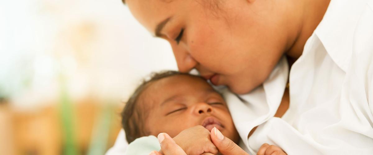 Close up photo of a mother kissing her baby's head