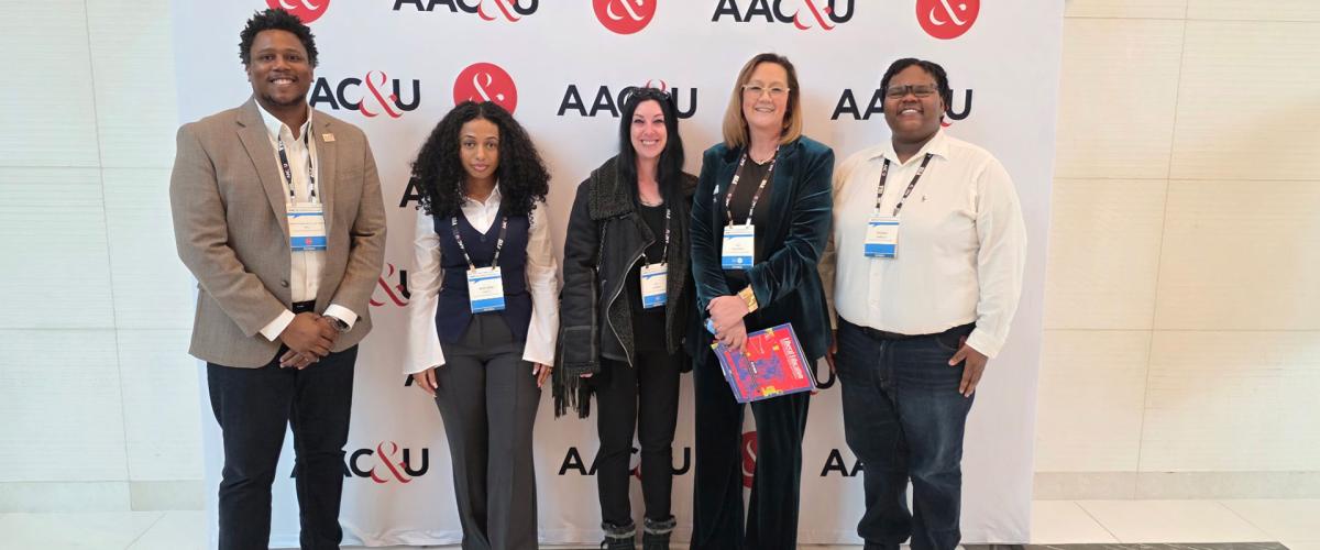 Photo of five people posing for a photo at a conference