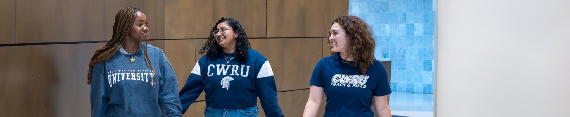 Three CWRU students walking together wearing spirit wear.