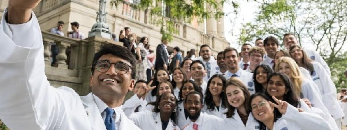A large group of whitecoat students posing on the steps for a photo