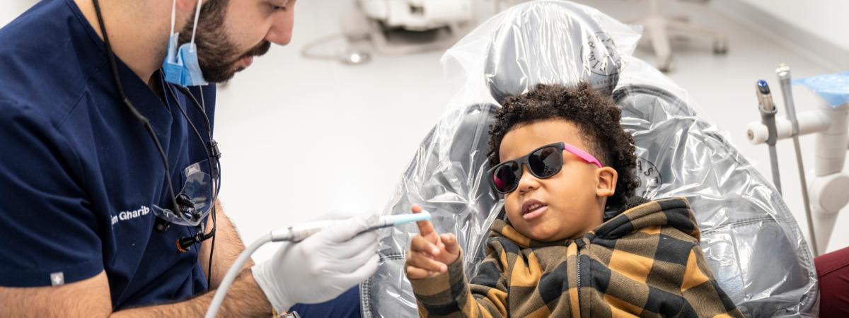 CWRU School of Dental Medicine student Karim Gharib shows dental tools to a child in the dental chair.