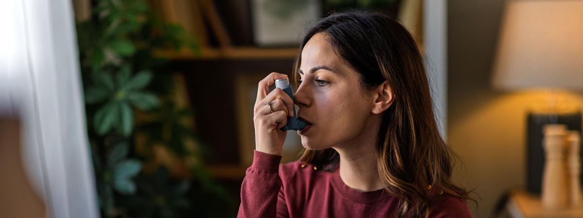 Photo of a woman sitting in her home using an inhaler