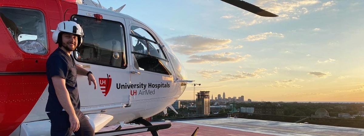 CRNA student Robert Sharkey stands in front of a medical helicopter on a rooftop.