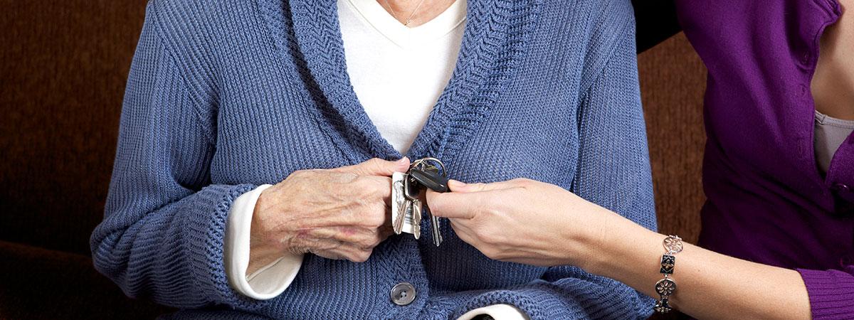 Photo of an elderly woman handing car keys to another person