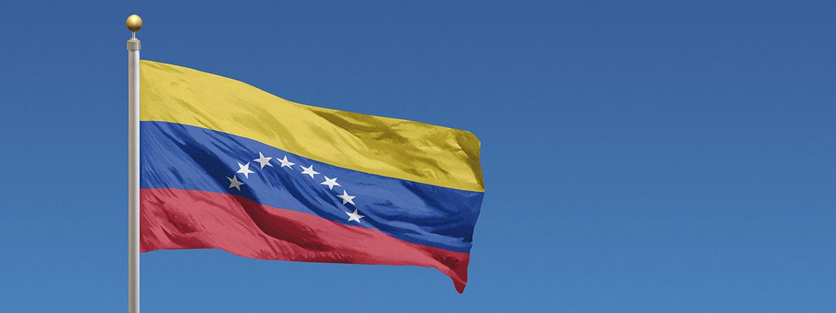 Photo of the Venezuelan flag flying against a blue sky