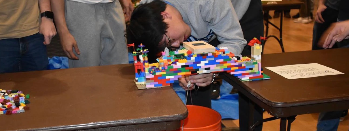 A student tests their lego bridge stability during a 2025 E-Week event