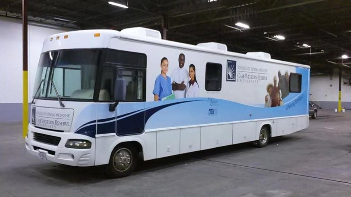 The white and blue CWRU dental clinic bus sits in a garage.